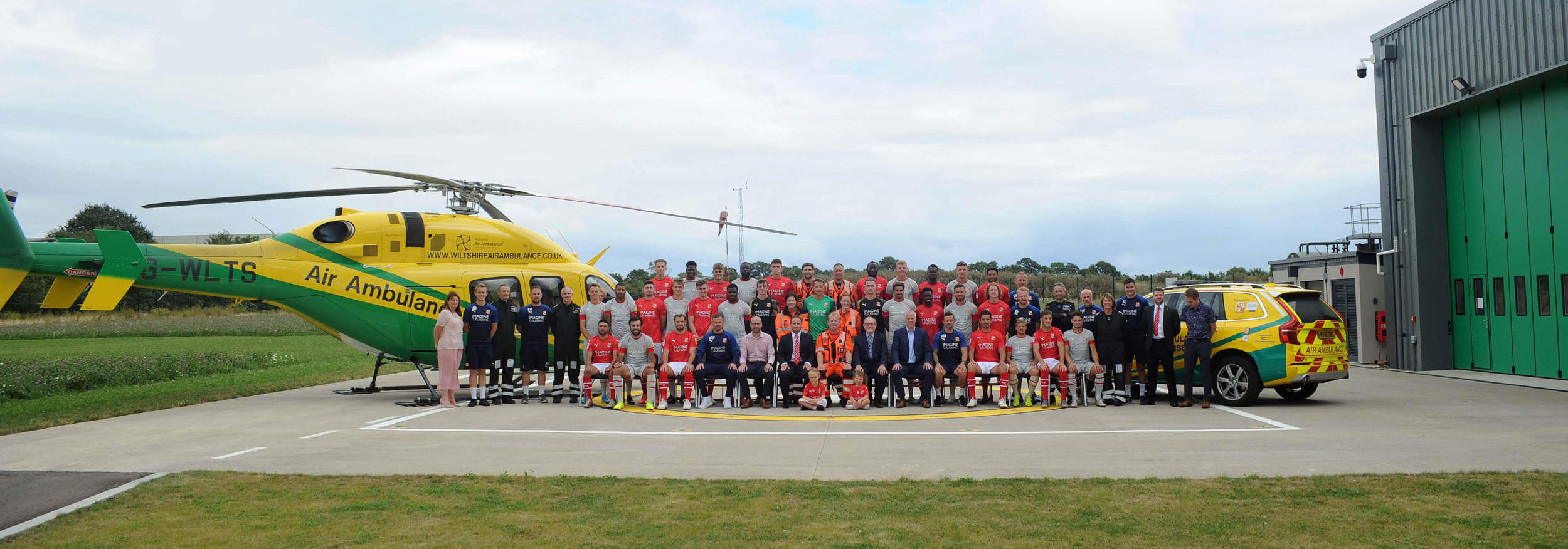 Swindon Town Football Club players official team photo for the 2019/20 season with the Wiltshire Air Ambulance helicopter and critical care car, on WAA's helipad