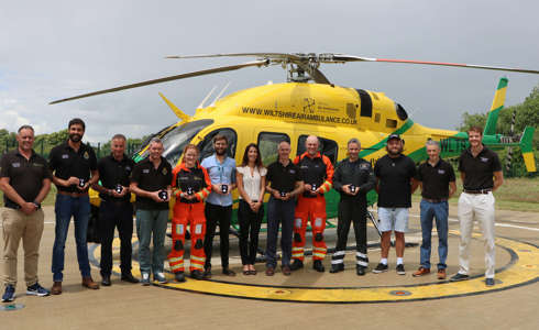 A photo of critical care paramedics and pilots in front of the Bell-429 helicopter on the helipad holding Platinum Jubilee award medals.