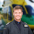 Pilot Rob Collingwood stood smiling with a blurred helicopter background.
