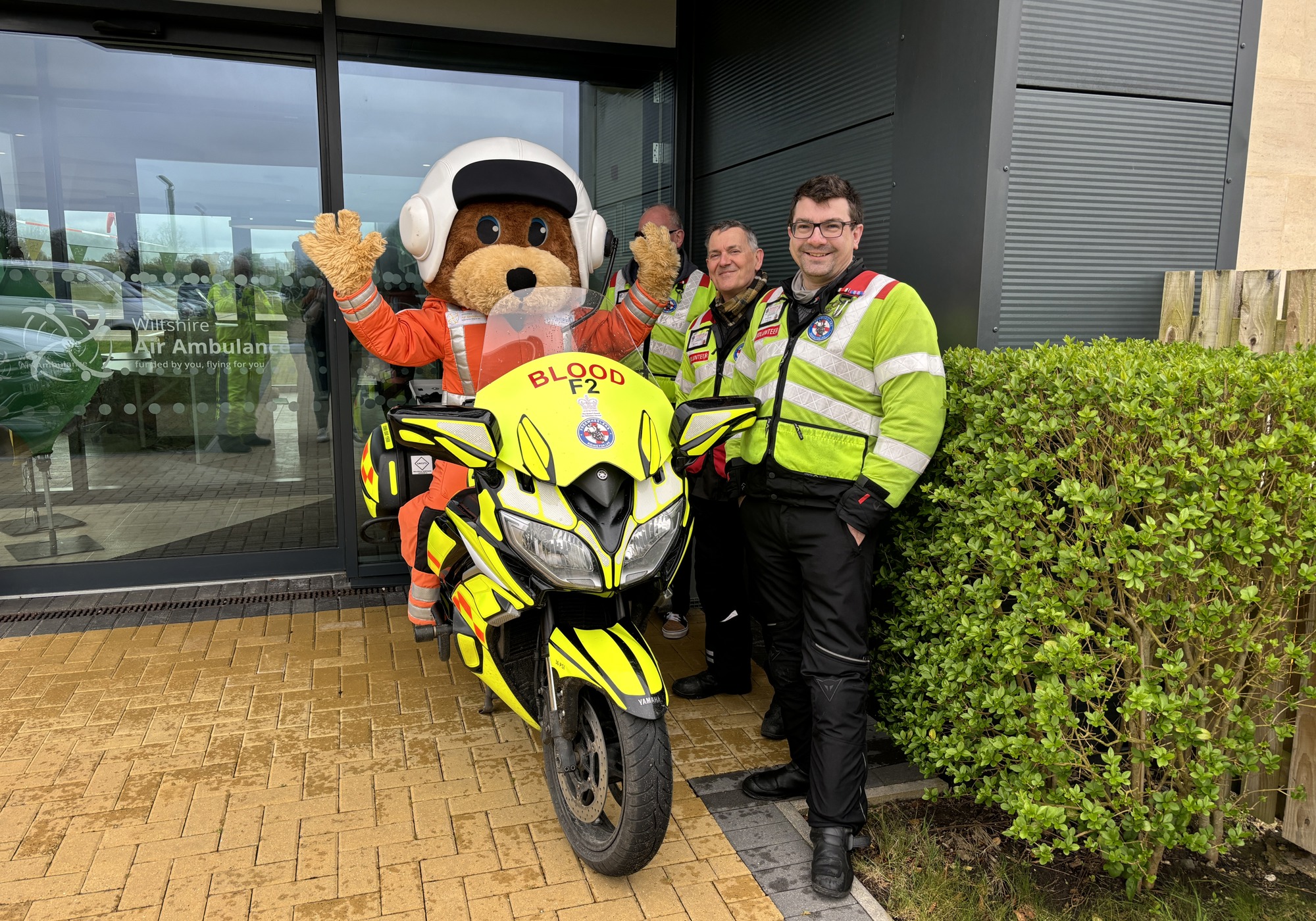 A paramedic bear mascot on a blood bike, with three other blood bikers posing
