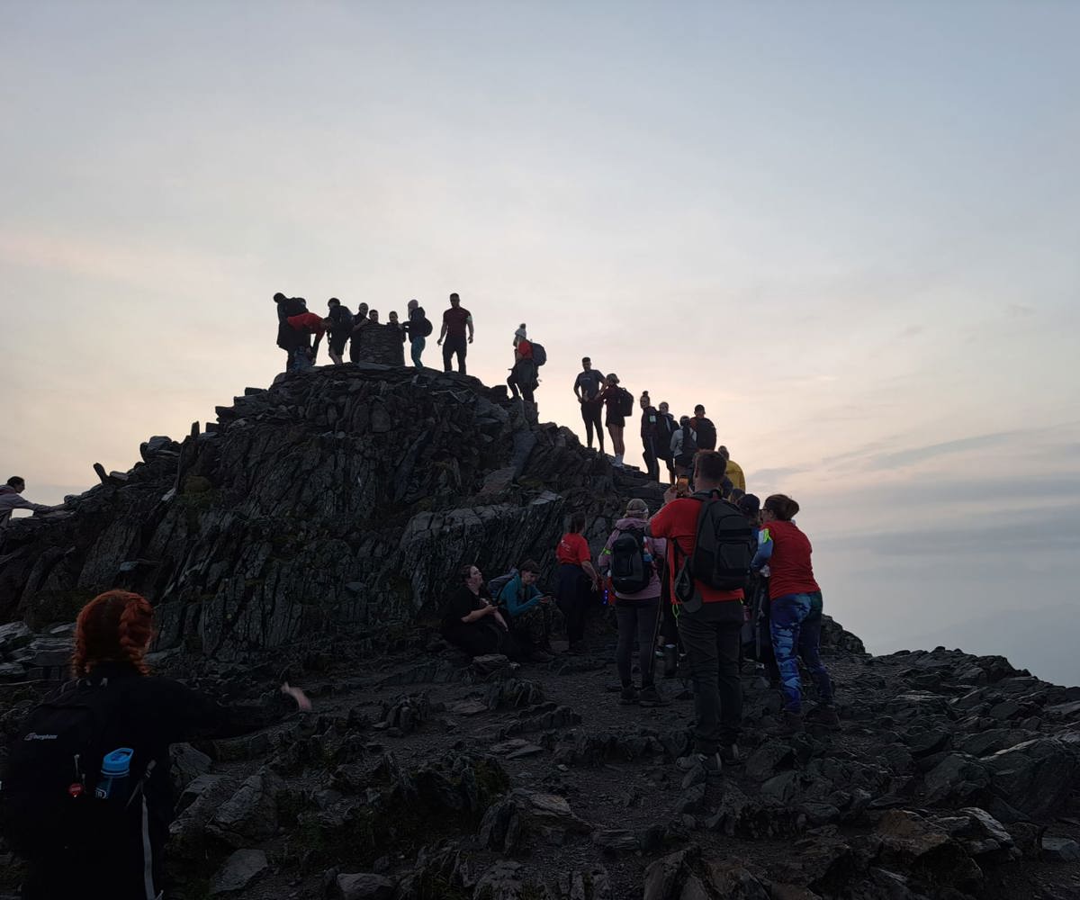 A photo of people climbing Mount Snowdon as the sun rises