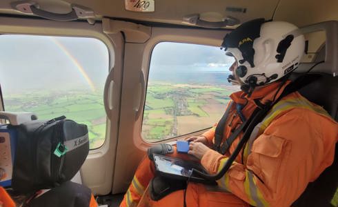 A critical care doctor in an air ambulance, looking out the window to see a rainbow