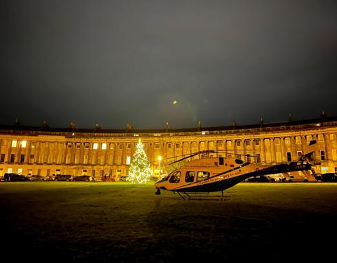 Wiltshire Air Ambulance landed at Royal Crescent, Bath at night, in front of a lit christmas tree