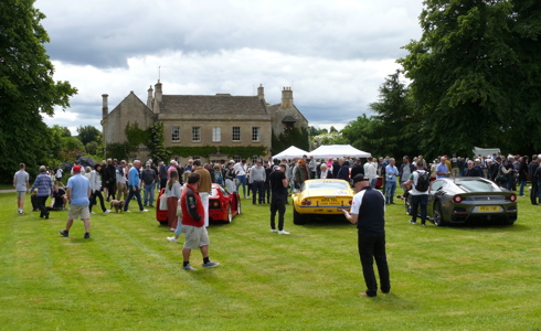 A photo of a house and cars, with people walking around