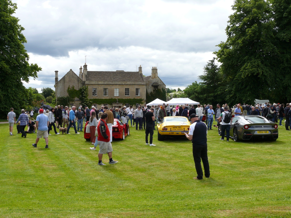 A photo of a house and cars, with people walking around