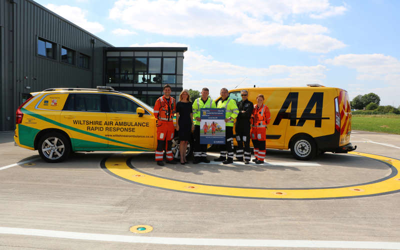 A group photo on the helipad with the critical care car and AA recovery van featuring a paramedics and staff from the AA.