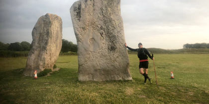 A supporter wearing black sports gear who is stood next to the Avebury Stones after taking part in the Race to the Stones event.