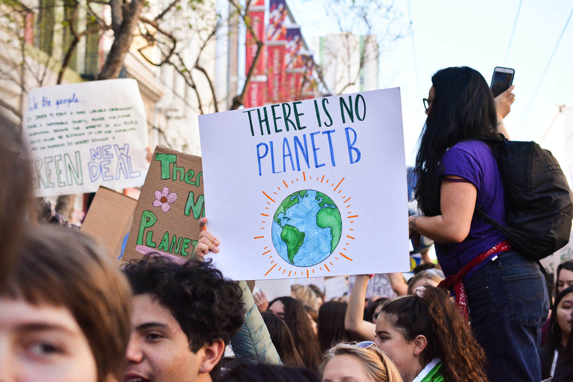 A person holding a sign with an illustration of the earth with the words 'There is no planet B'