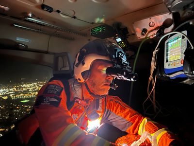 Paramedic Paul Rock wearing flight helmet and night vision goggles Treating a Patient whilst flying in the Wiltshire Air Ambulance At Night