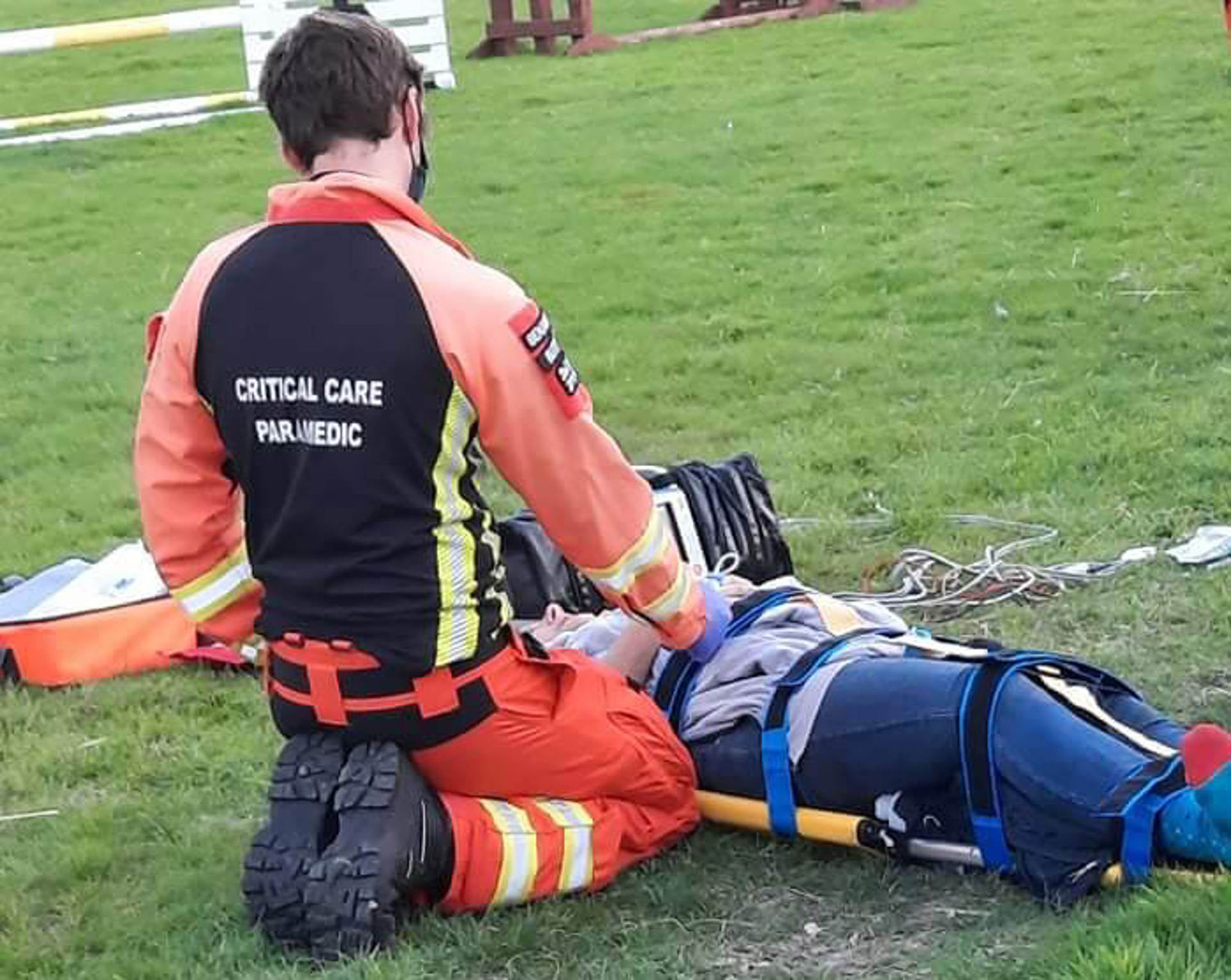 A patient laying on a stretcher with a critical care paramedic knelt by their side