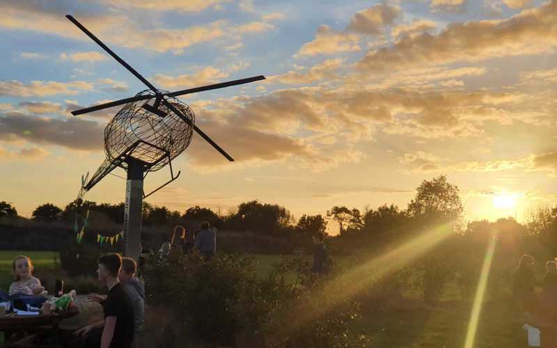 People enjoying the sunset, below a model of the helicopter, at the Wiltshire Air Ambulance airbase