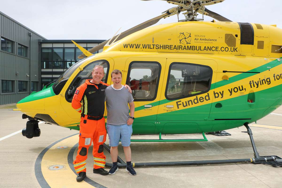 A former patient meeting critical care paramedic at the charity's airbase. They are stood in front of the helicopter on the helipad.