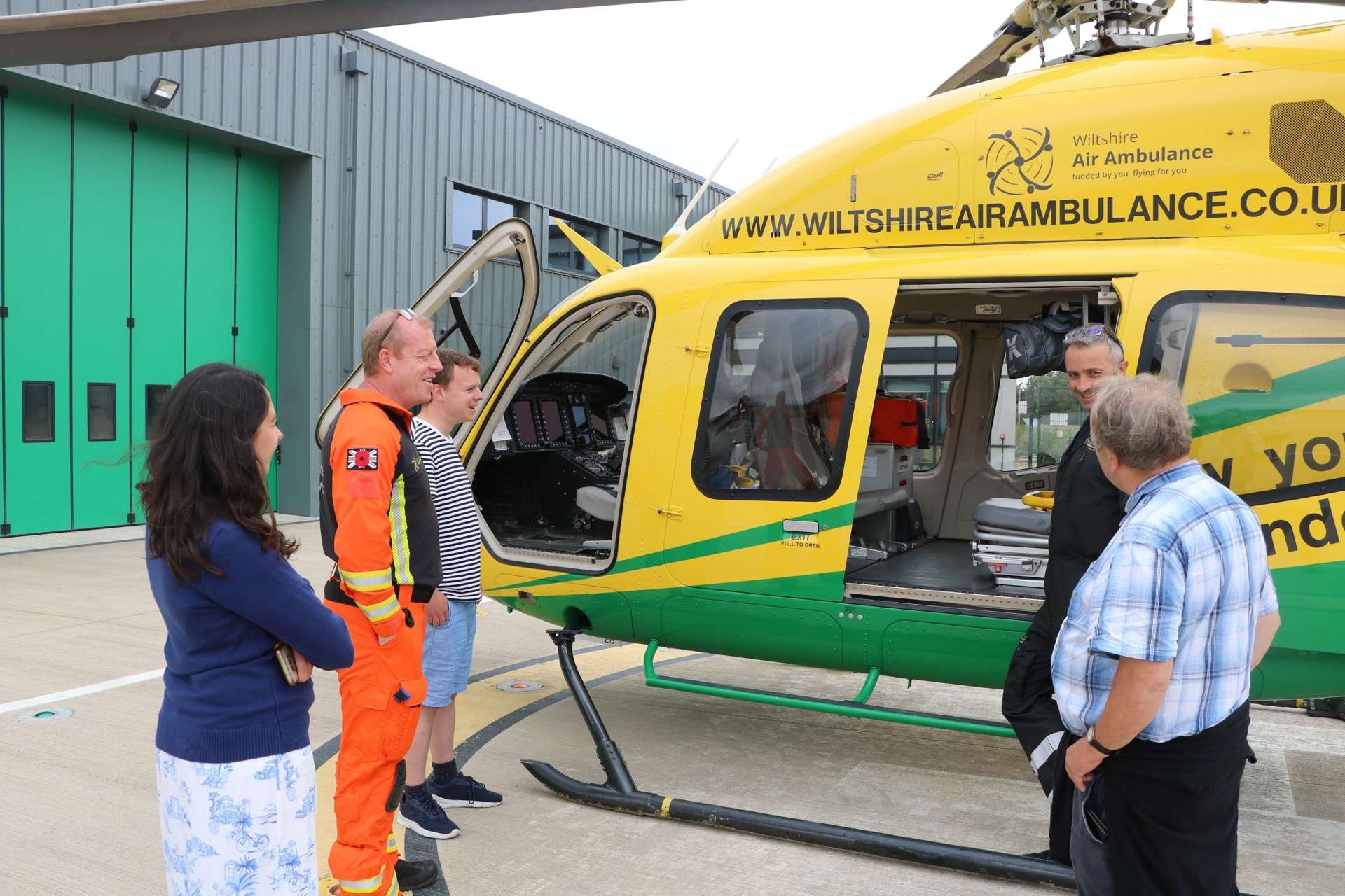 A former patient speaking to a pilot and paramedic next to the Bell-429 helicopter