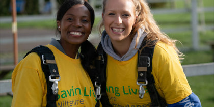 Two people wearing yellow t-shirts and GoSkydive overalls at a skydive event