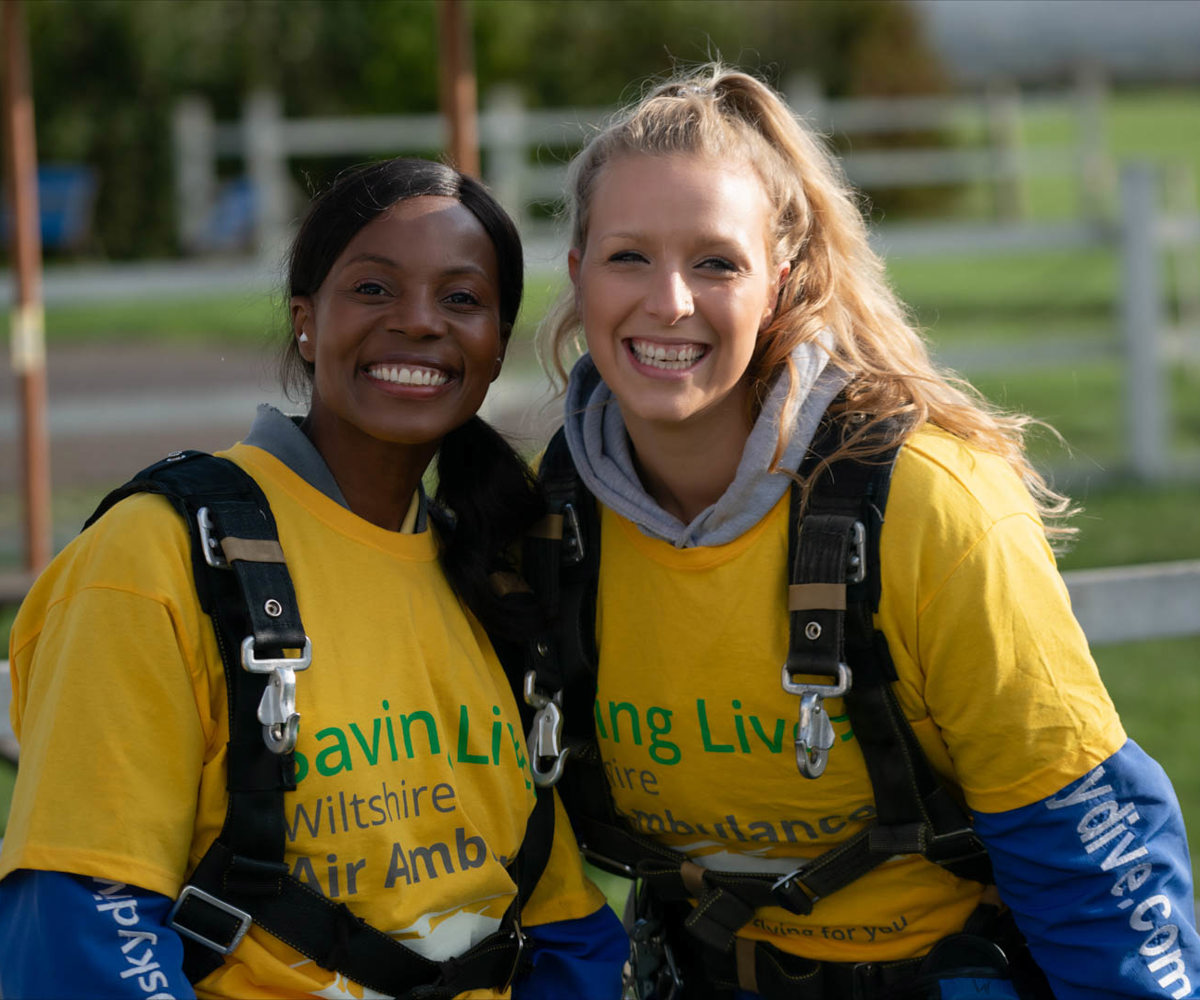 Two people wearing yellow t-shirts and GoSkydive overalls at a skydive event