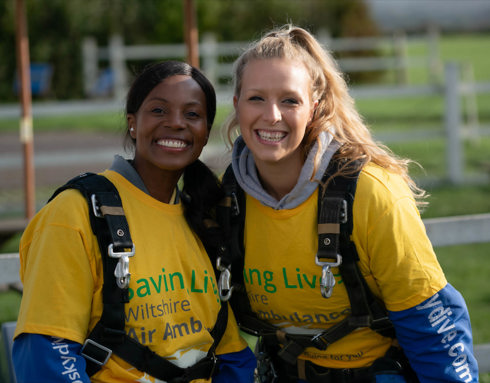 Two people wearing yellow t-shirts and GoSkydive overalls at a skydive event