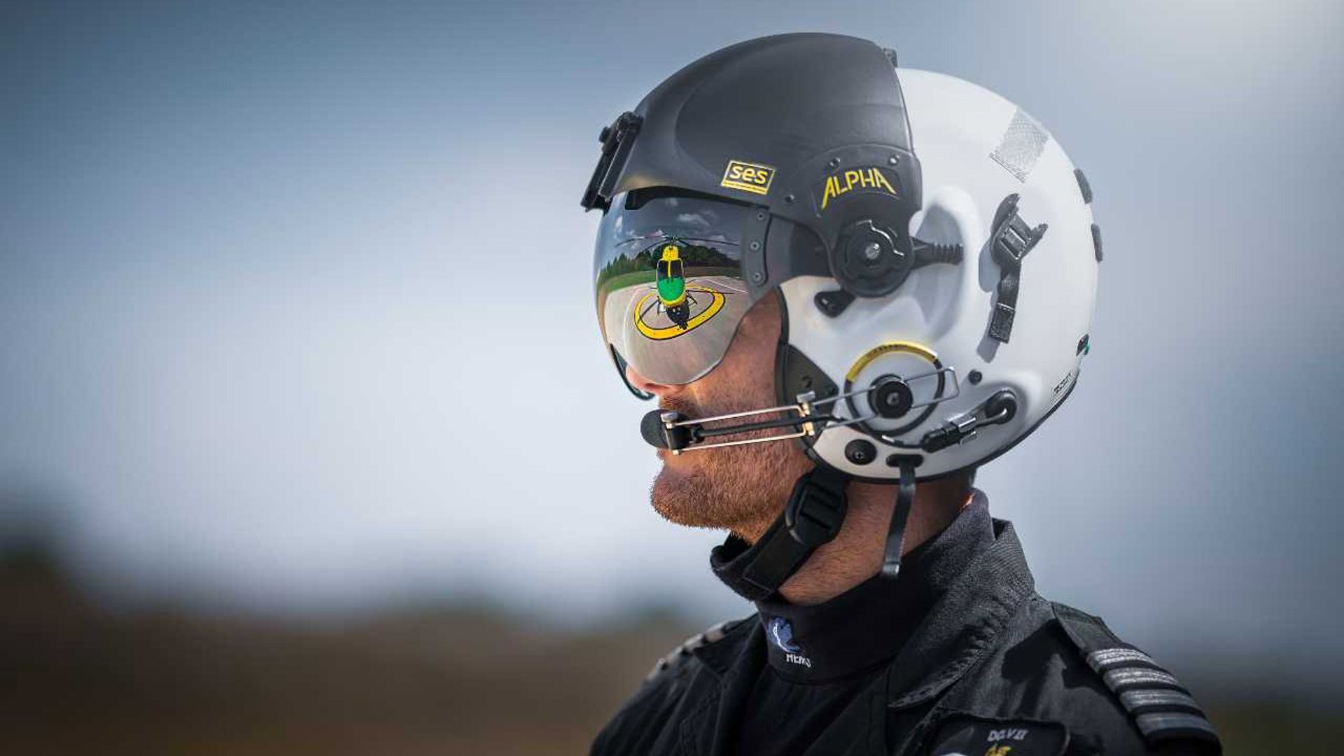 Pilot Rob Collingwood looking at the helicopter whilst wearing a flight helmet and visor. There is a reflection of the helicopter in the visor.