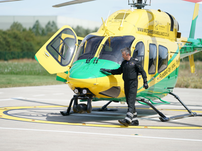 Pilot Matt with hand on nose of Wiltshire Air Ambulance's helicopter
