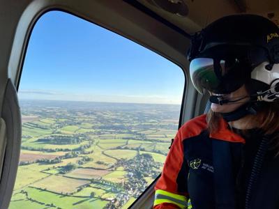 Dr Rosie Furse in the Wiltshire Air Ambulance helicopter admiring the view from above of green fields and sunny skies.