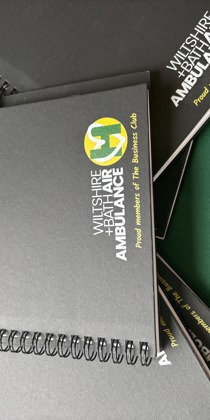 Black notebook and pen with yellow and green Wiltshire and Bath Air Ambulance logo