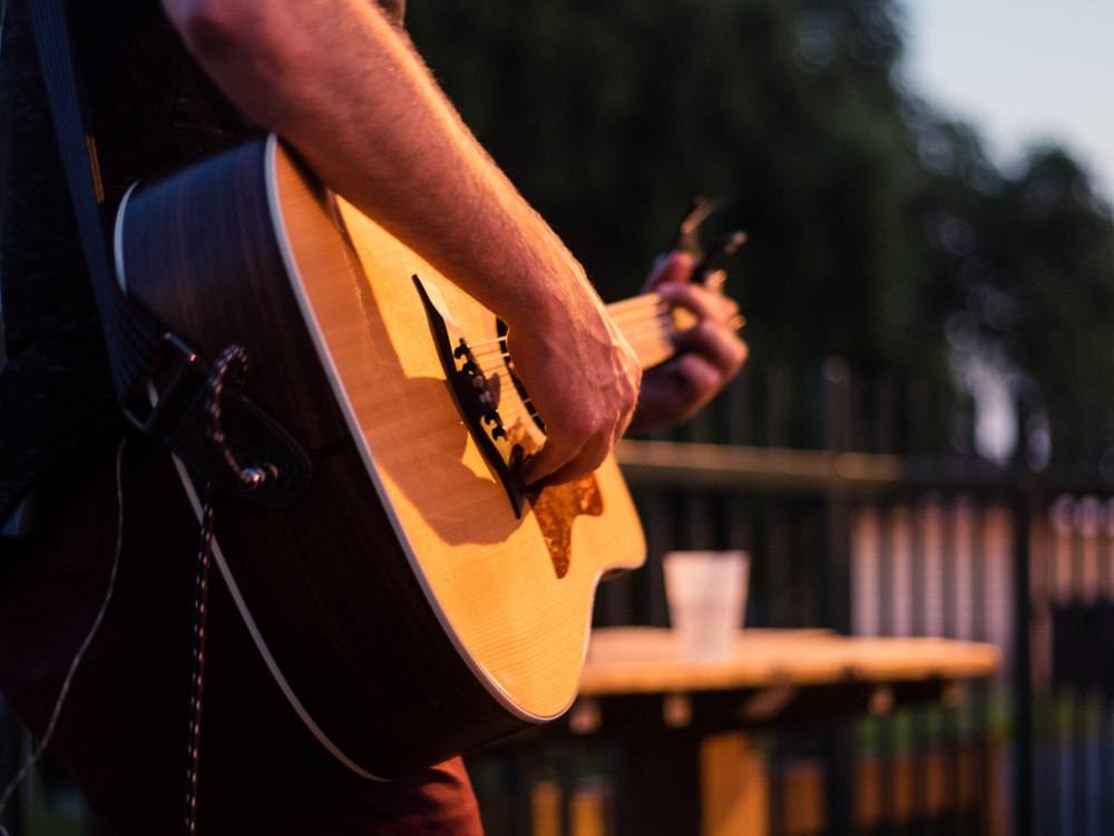 A person playing a guitar at an outdoor venue