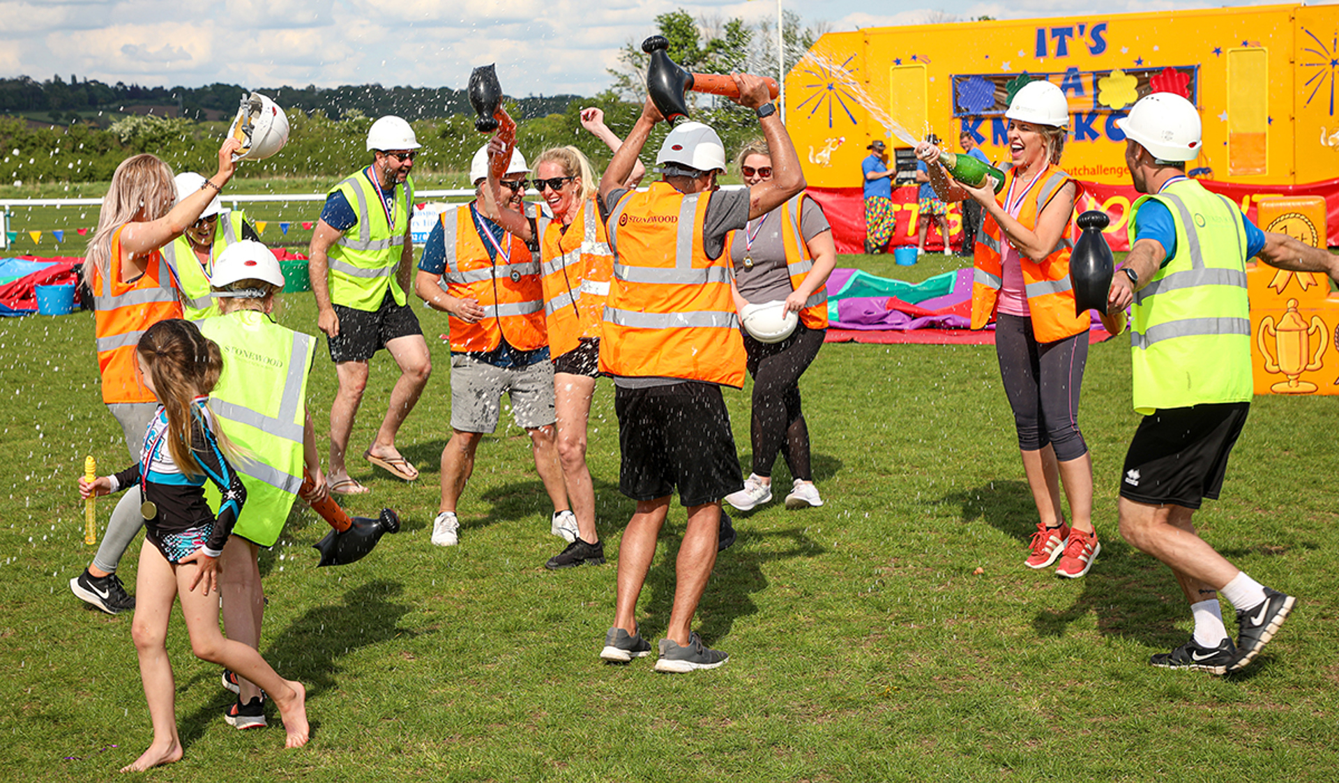 A group of supporters celebrating their win at It's a Knockout event with champagne