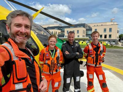 Dr Reuben, paramedics Sophie and Craig and Pilot Si standing on a helipad with Wiltshire Air Ambulance's helicopter in the background