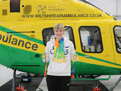 Lauren Booth posing in front of the helicopter with their gold medals