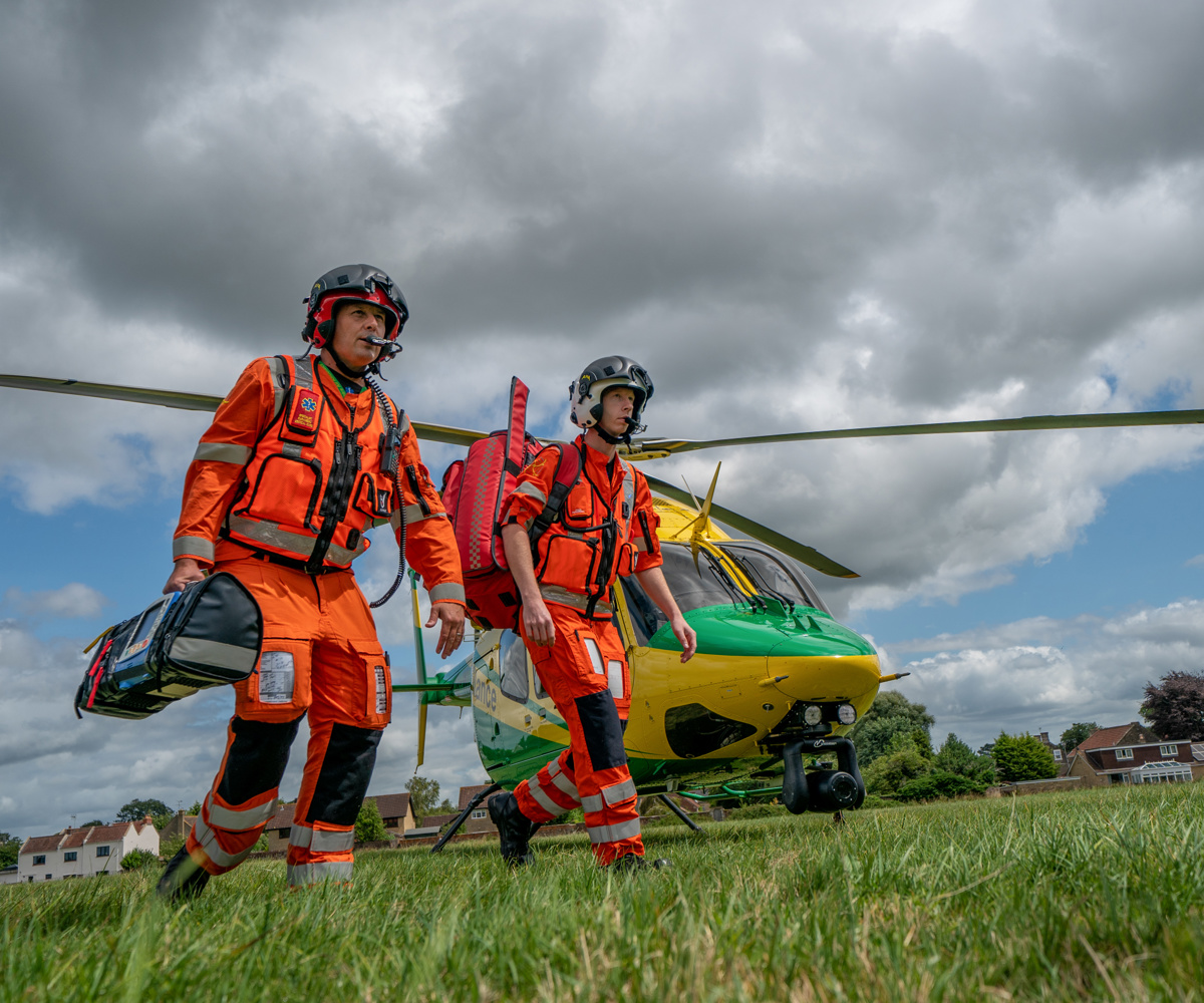 Two paramedics walking away from the helicopter towards a staged incident in a field