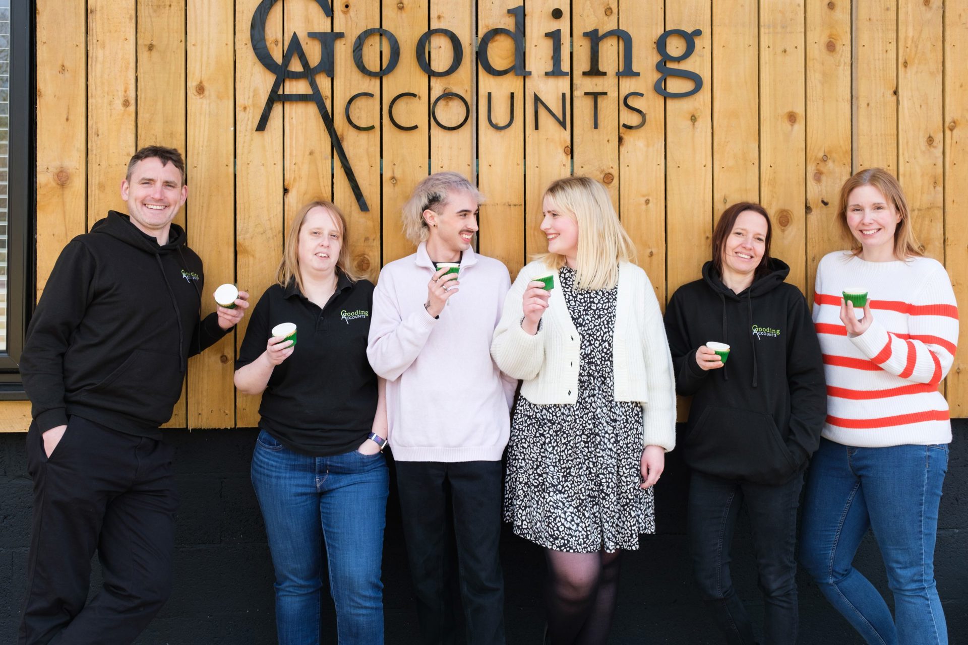 6 people standing in front of a Gooding Accounts sign