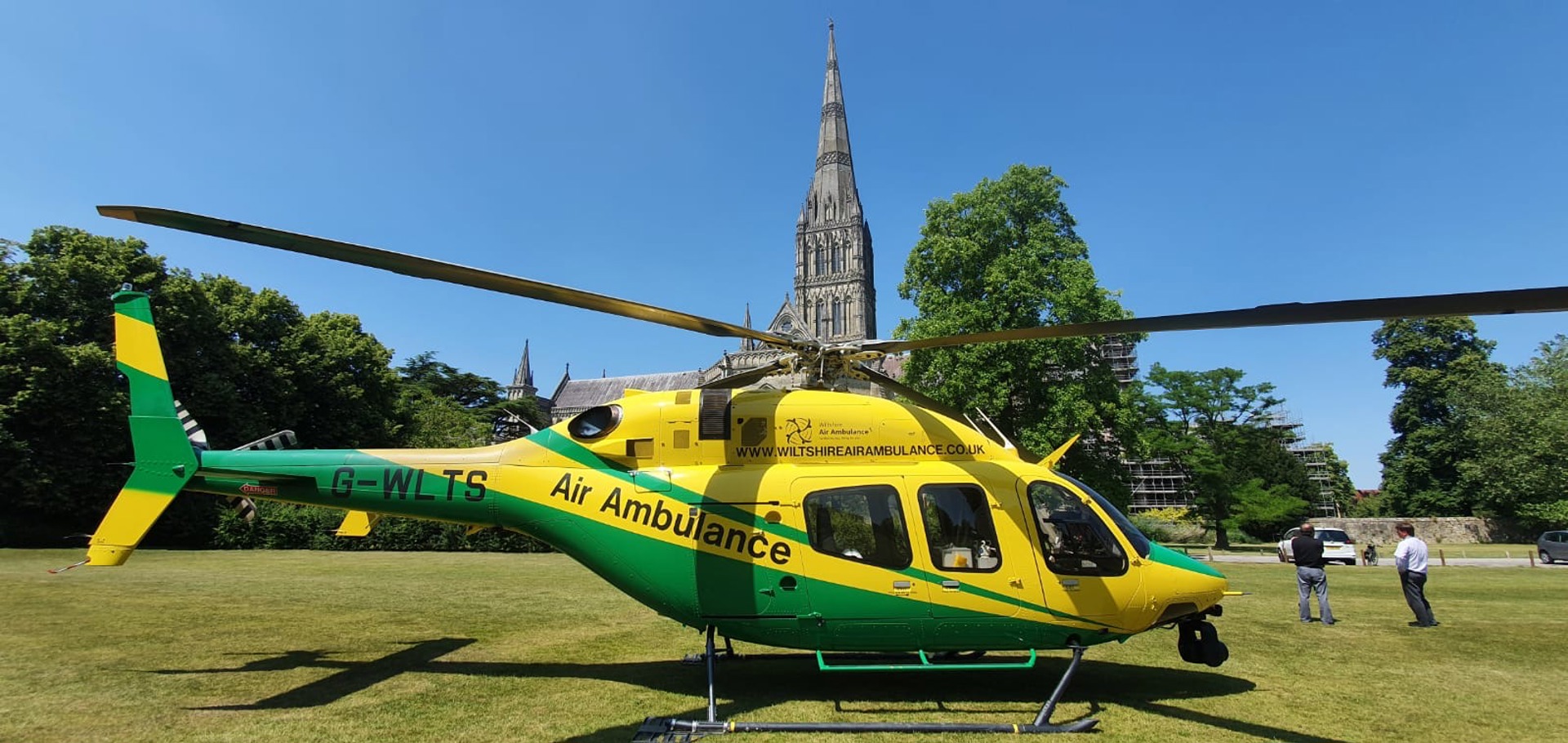 Yellow and green helicopter landed next to Salisbury Cathedral