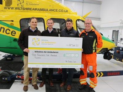 The Jockey Club presenting Paramedic Keith Mills with a cheque of £3,500 standing in front of the Wiltshire Air Ambulance helicopter