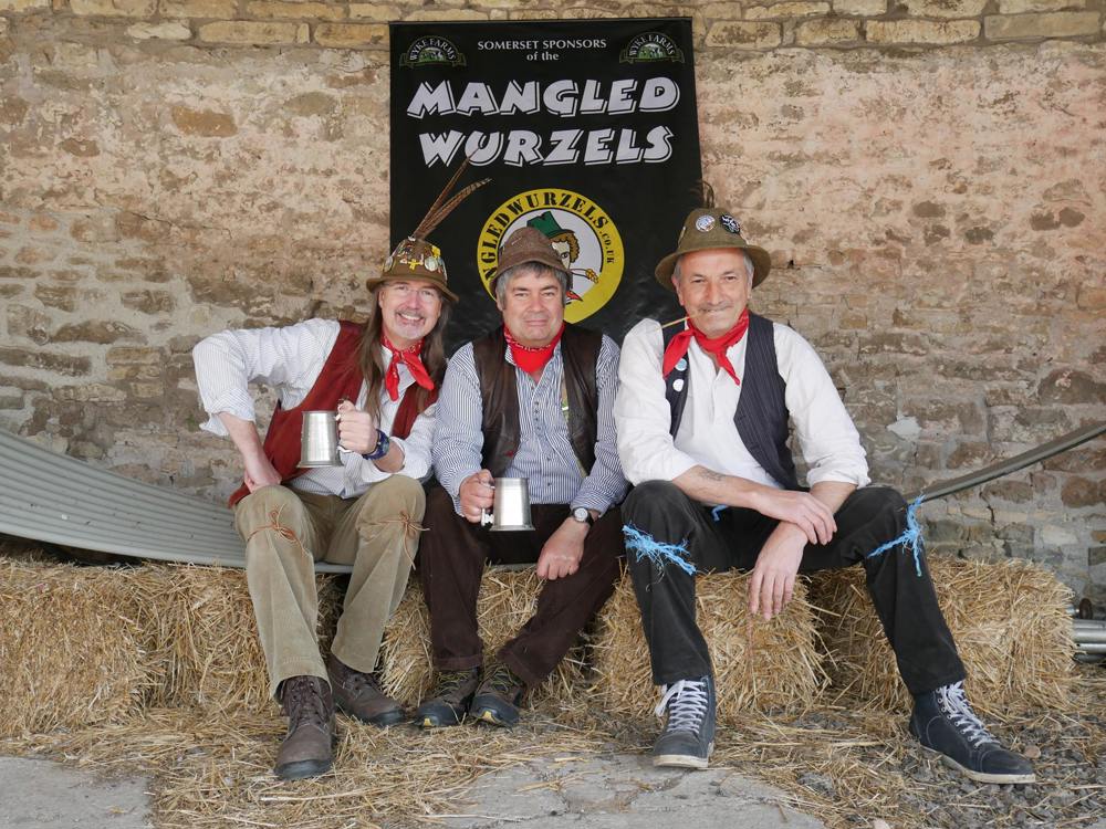 A photo of The Mangled Wurzels sitting on bales of hay