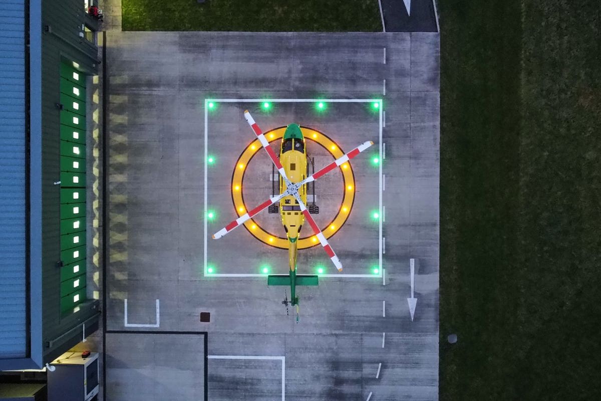 An aerial view of the WAA helicopter on a lit helipad at the charity's airbase