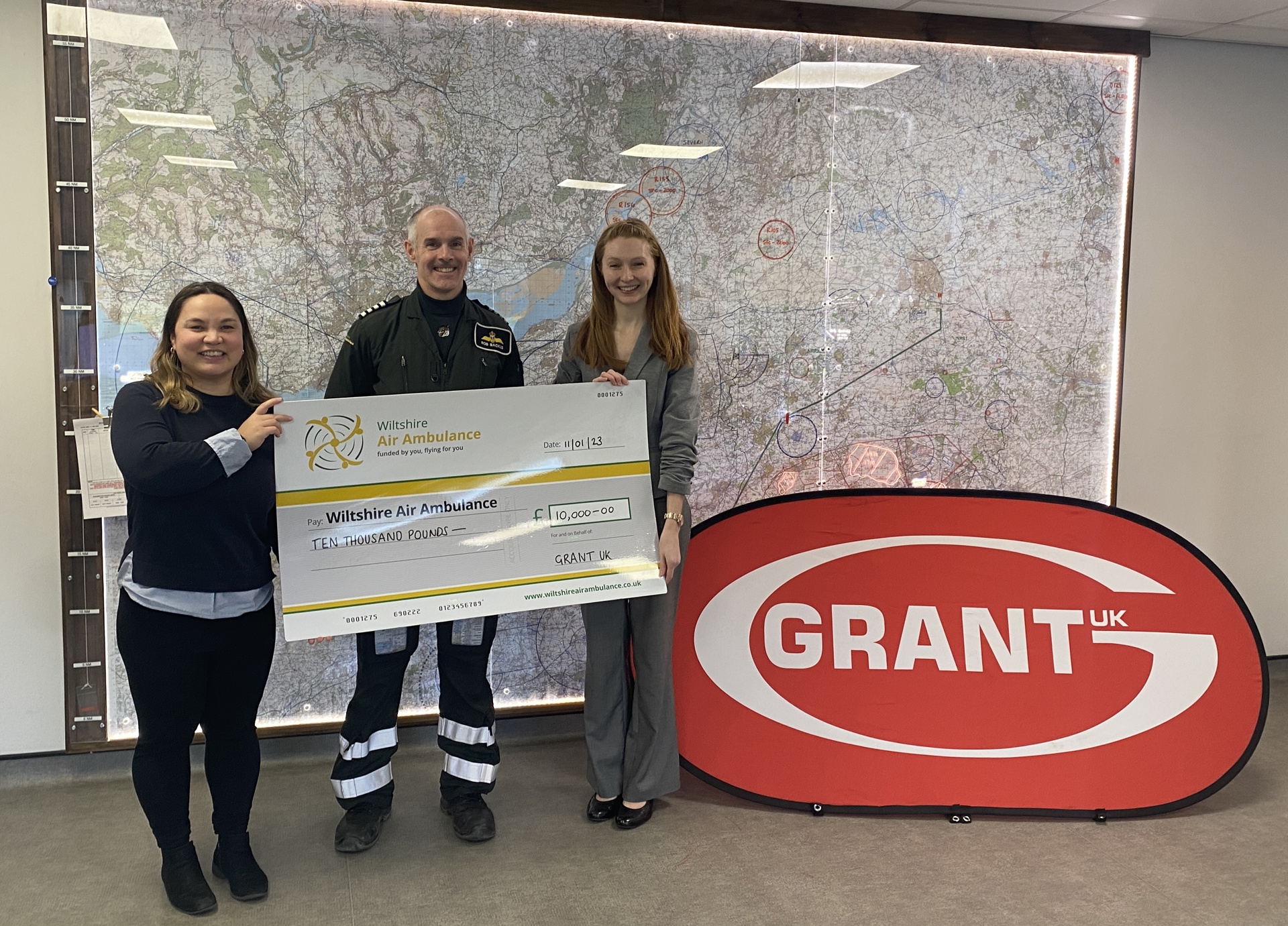 A cheque presentation from staff at Grant UK in the flight room at Wiltshire Air Ambulance's airbase
