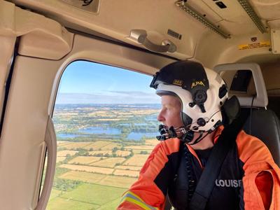Paramedic wearing a flight helmet Lou Cox and Looking Out Window of Wiltshire Air Ambulance helicopter