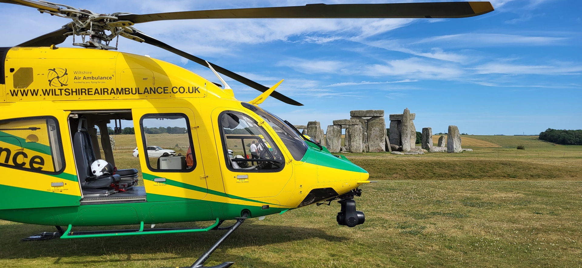 A yellow and green helicopter landed near Stonehenge