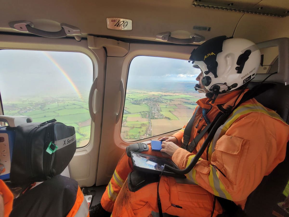 A critical care doctor in an air ambulance, looking out the window to see a rainbow