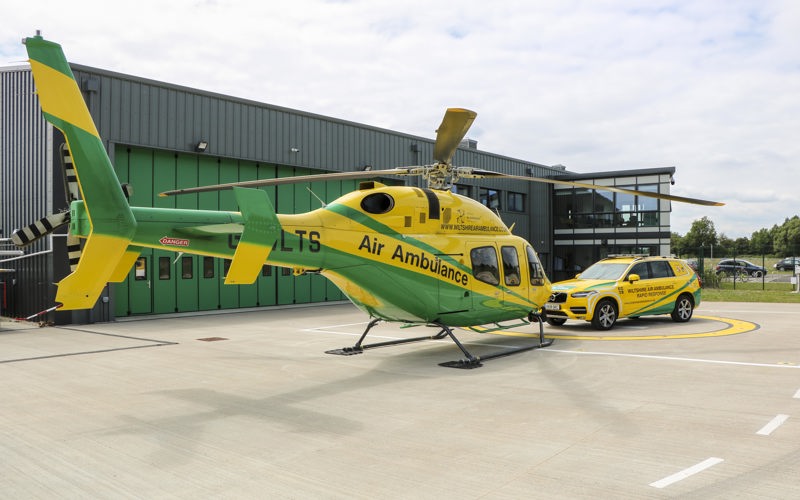 The Wiltshire Air Ambulance helicopter and critical care car on the helipad at the airbase.