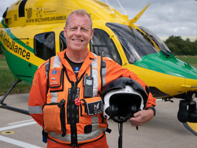 Critical care paramedic Keith Mills on the helipad with the Wiltshire Air Ambulance helicopter in the background.