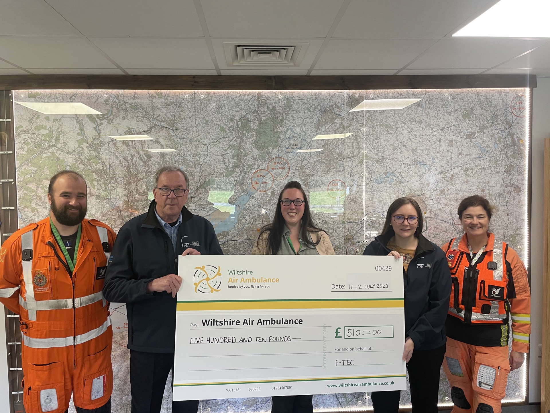 A group of staff holding a giant cheque for Wiltshire Air Ambulance